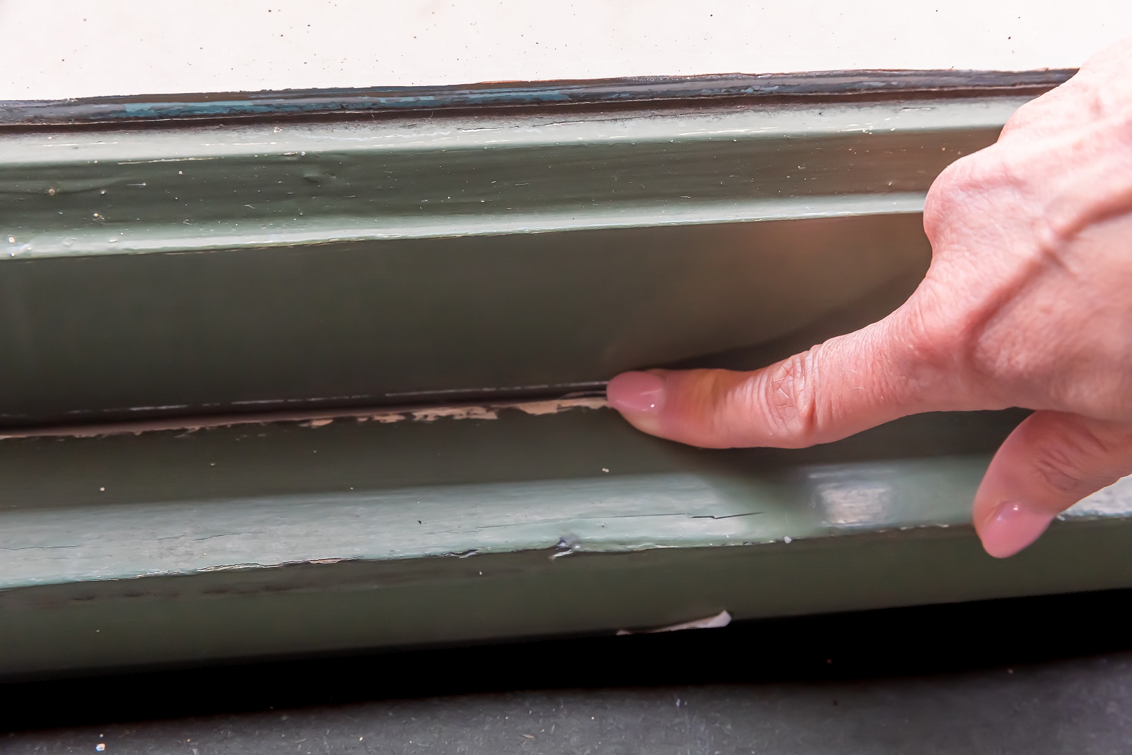 Iemand controleert of er al tochtband zit in de kier tussen de sponning en het raam.