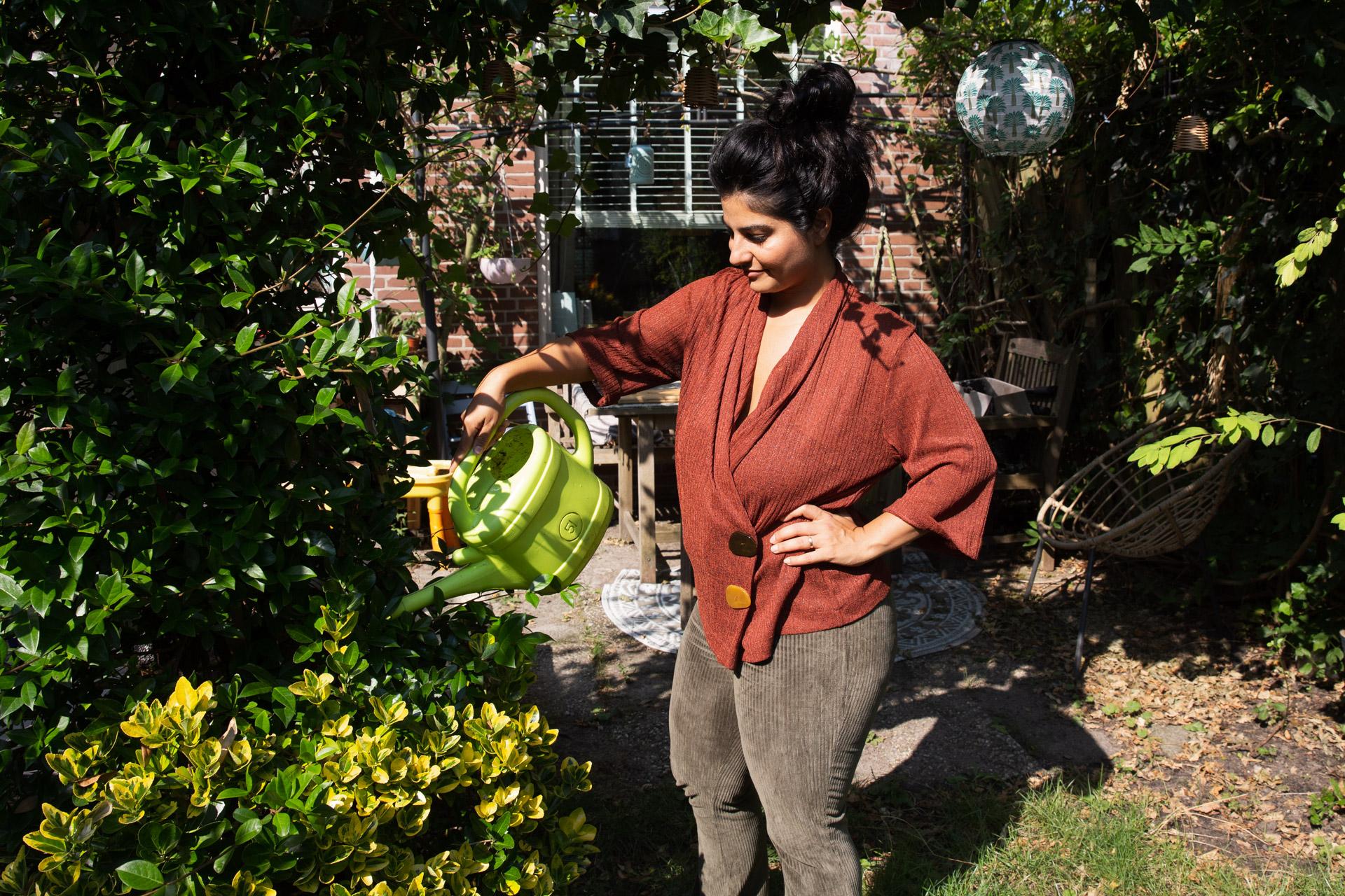 vrouw geeft planten water met gieter in tuin