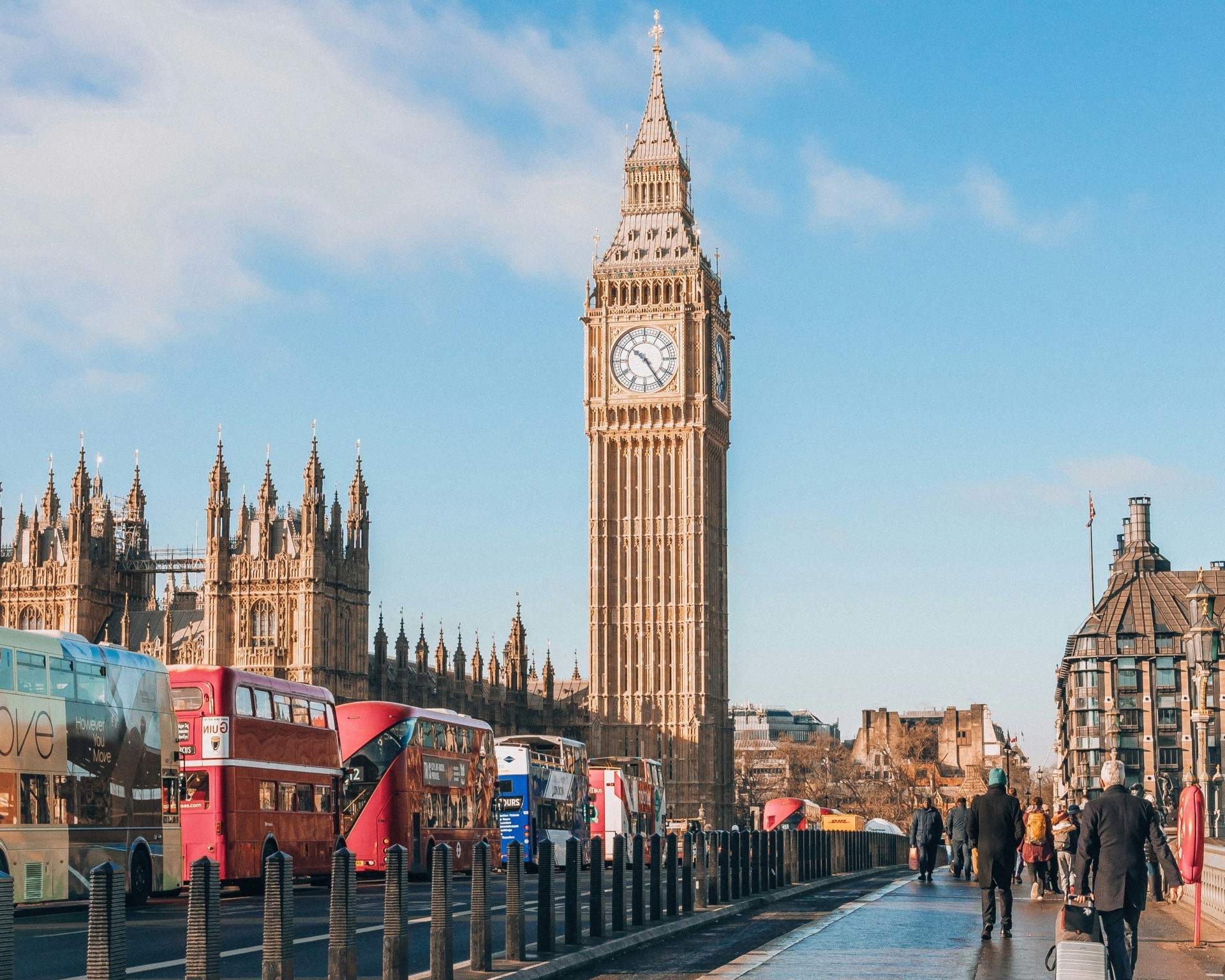 Foto van de Big Ben in Londen. Op de voorgrond rijden dubbeldekkerbussen.