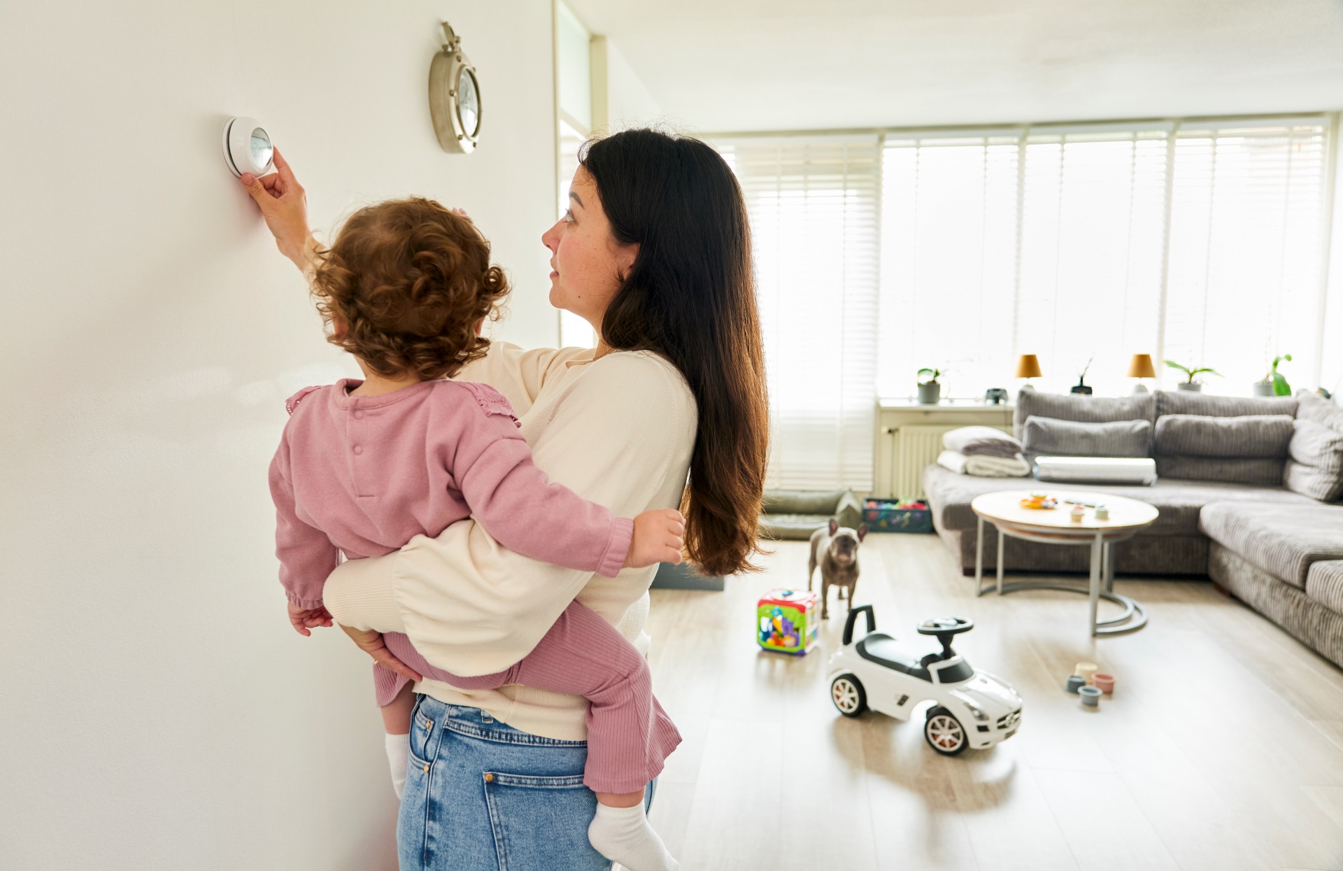 Vrouw met kind op de arm staat bij thermostaat